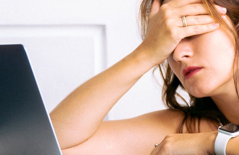 exhausted woman at her computer feeling stressed