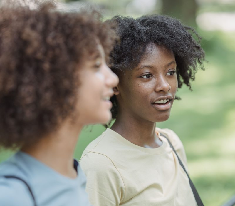 two young ladies talking outside while walking